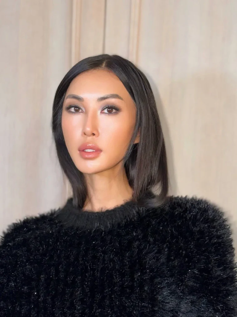 Woman with a sleek dark bob and glowing makeup wearing a black fuzzy sweater